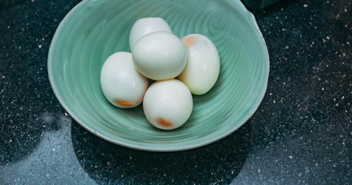 Peeled hard boiled eggs in a green bowl