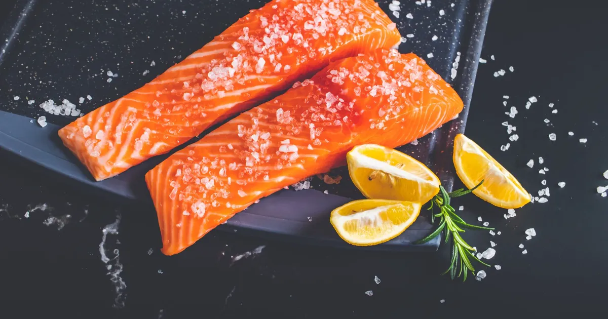 Raw salmon fillets with salt, lemon wedges and rosemary